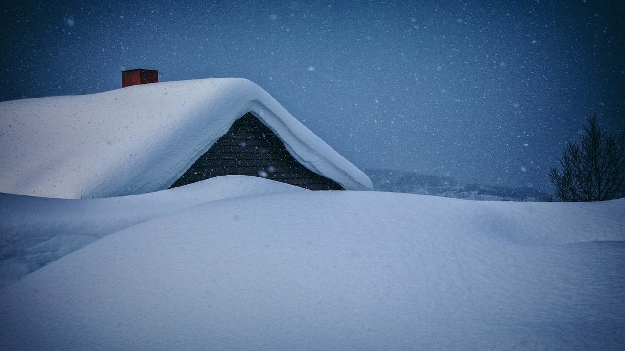 Casă rezidențială acoperită de un strat consistent de zăpadă curată în toiul iernii