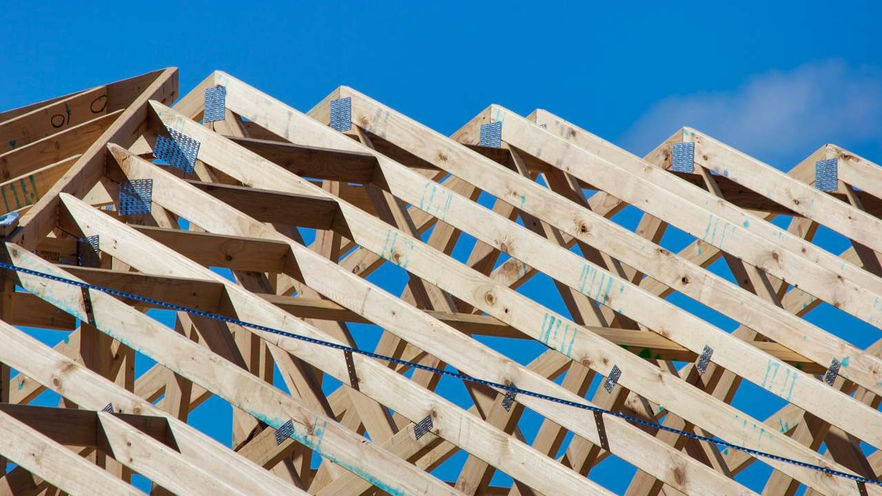 Șarpantă nouă din lemn la o casă în construcție, cu căpriori pe fundal de cer albastru